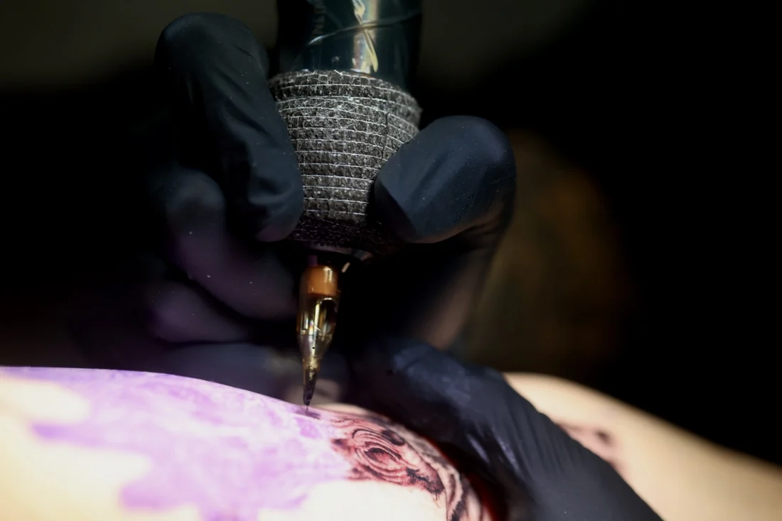 Close detail of the needle meeting the skin, at Pangea Ink