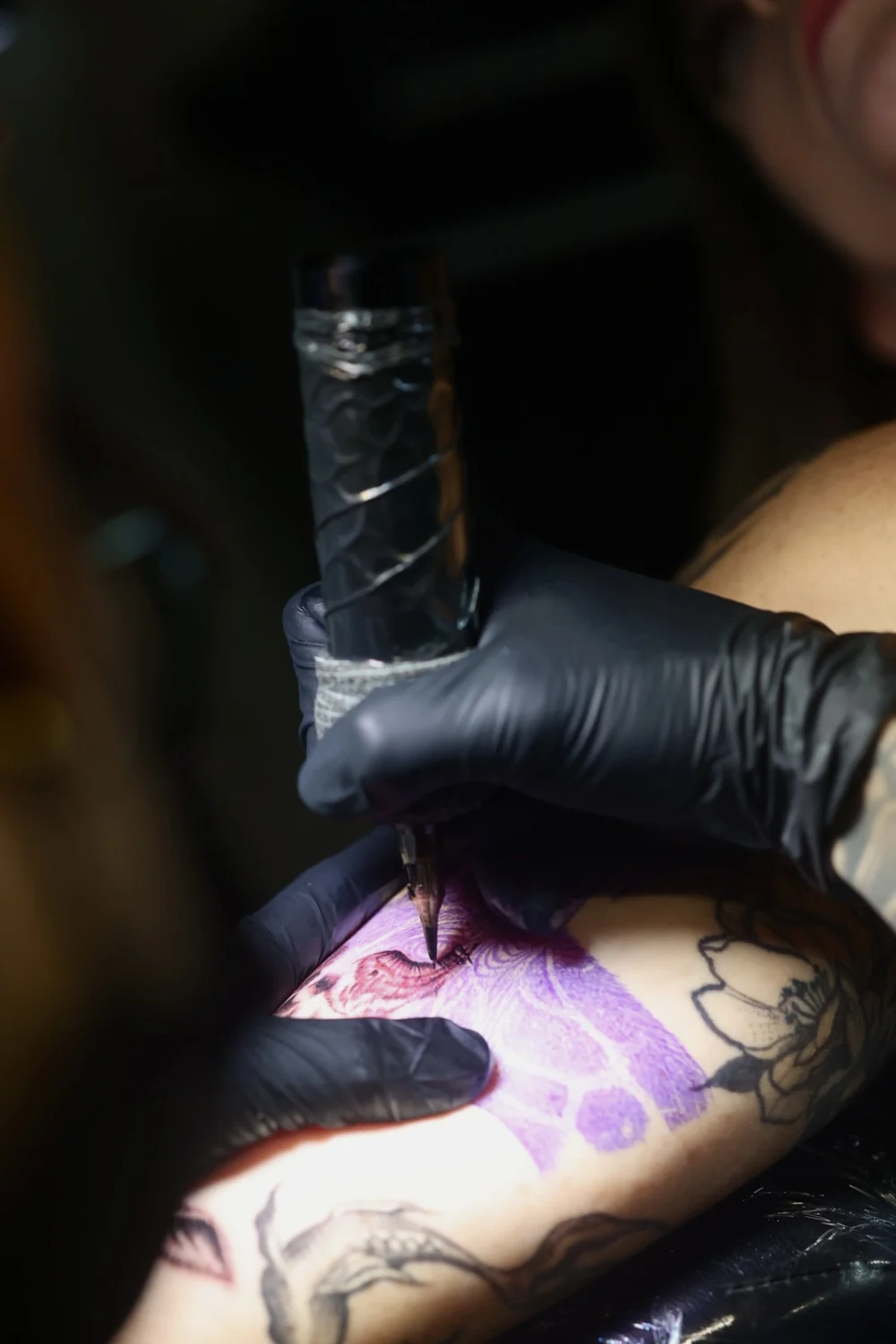 Machine working over a purple stencil on the arm, at Pangea Ink
